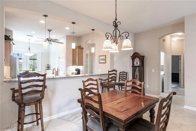dining space featuring ceiling fan, arched walkways, light tile patterned floors, baseboards, and recessed lighting