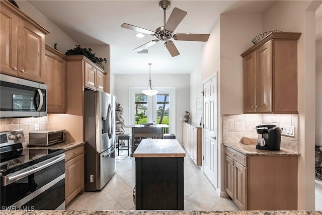 kitchen with a center island, decorative backsplash, stainless steel appliances, and light tile patterned floors