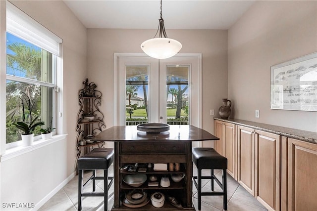 dining area featuring a healthy amount of sunlight, baseboards, and light tile patterned flooring