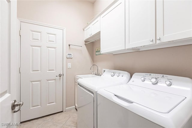 clothes washing area with washer and dryer, light tile patterned flooring, a sink, and cabinet space