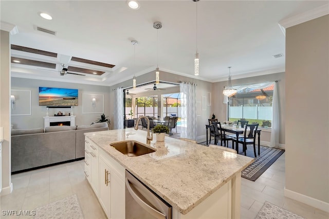 kitchen with light stone counters, an island with sink, dishwasher, sink, and decorative light fixtures