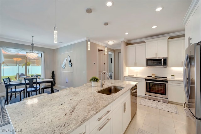 kitchen featuring sink, hanging light fixtures, white cabinetry, stainless steel appliances, and a kitchen island with sink