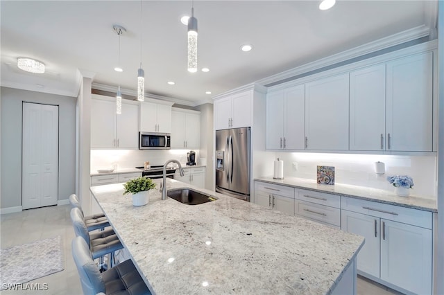 kitchen featuring white cabinets, appliances with stainless steel finishes, a kitchen island with sink, pendant lighting, and sink