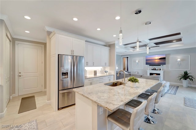 kitchen with sink, decorative light fixtures, white cabinets, stainless steel fridge with ice dispenser, and a kitchen island with sink