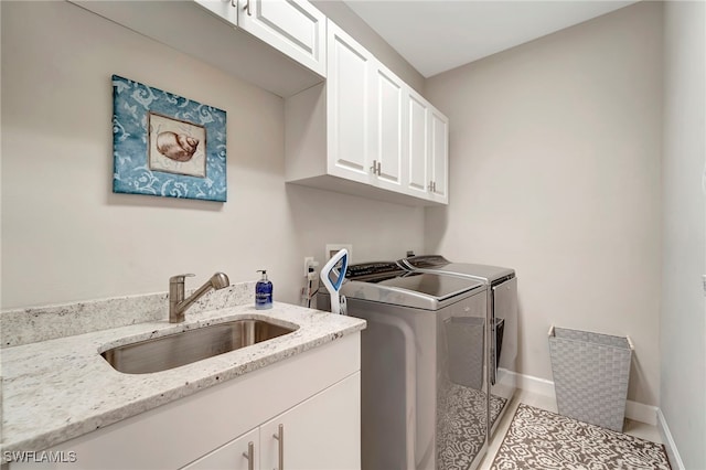 laundry area with cabinets, sink, separate washer and dryer, and light tile patterned floors