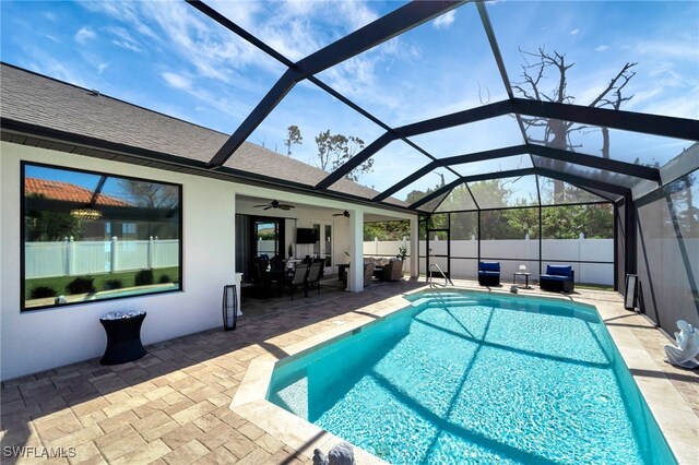 view of pool with ceiling fan, glass enclosure, and a patio area