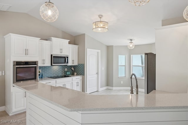 kitchen with white cabinetry, vaulted ceiling, stainless steel appliances, decorative light fixtures, and light stone counters