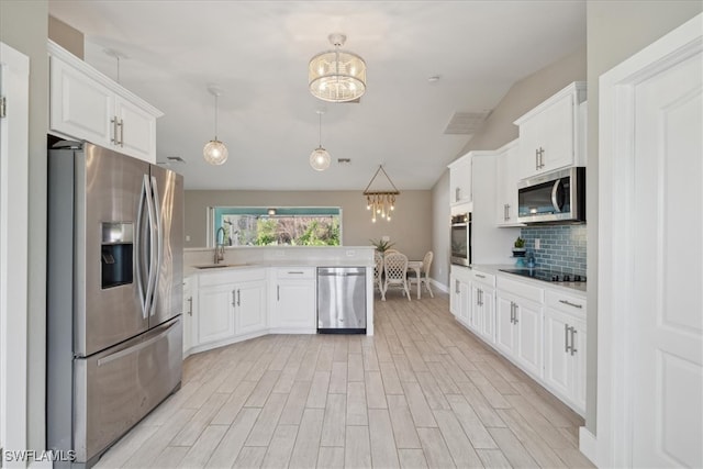 kitchen featuring light hardwood / wood-style floors, stainless steel appliances, pendant lighting, white cabinets, and decorative backsplash