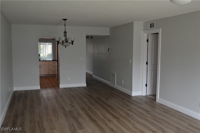 unfurnished dining area featuring a notable chandelier and dark wood-type flooring