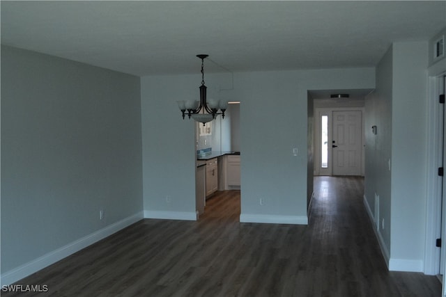 unfurnished dining area featuring dark hardwood / wood-style flooring and a chandelier