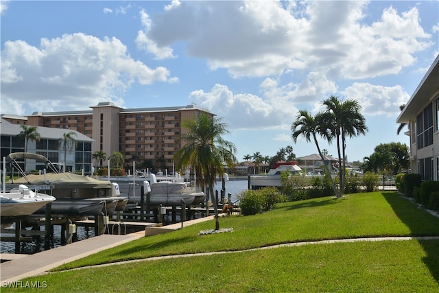 view of community with a dock, a water view, and a yard