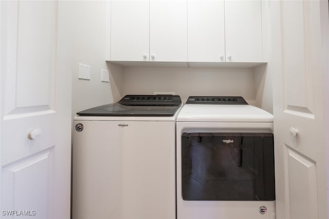 clothes washing area with independent washer and dryer and cabinets