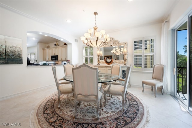 dining area with light tile patterned flooring, ornamental molding, and a chandelier