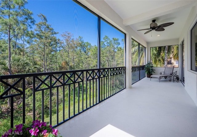 unfurnished sunroom with ceiling fan and beamed ceiling