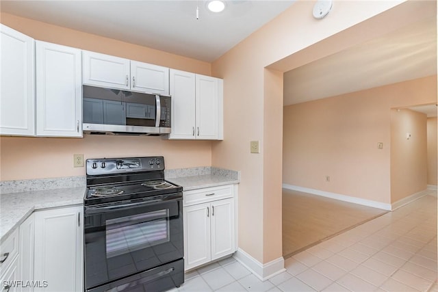 kitchen with light stone countertops, white cabinetry, black / electric stove, and light tile patterned flooring