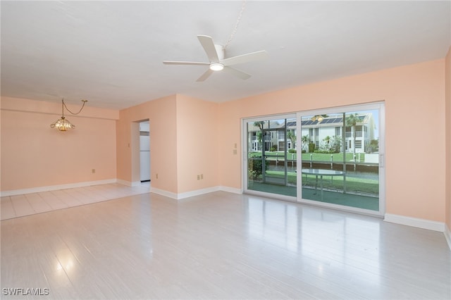 unfurnished room with ceiling fan with notable chandelier and light hardwood / wood-style floors