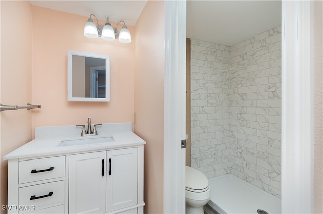 bathroom with a tile shower, vanity, and toilet