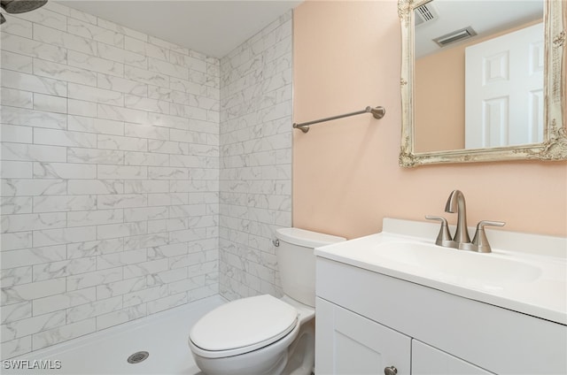 bathroom with vanity, toilet, and a tile shower