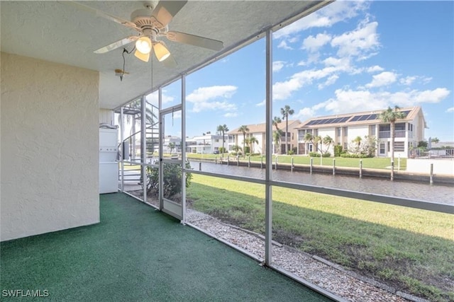 unfurnished sunroom with ceiling fan and a water view