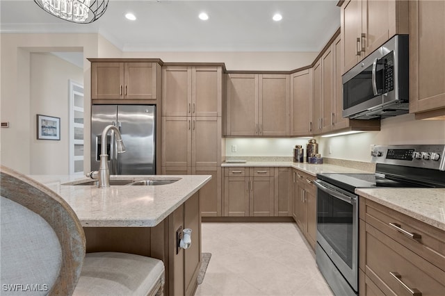 kitchen with ornamental molding, sink, an inviting chandelier, appliances with stainless steel finishes, and light stone counters