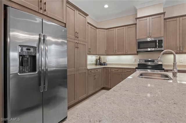 kitchen with appliances with stainless steel finishes, sink, and light stone counters