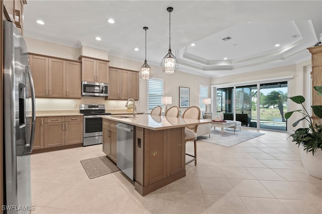 kitchen with hanging light fixtures, light stone countertops, a kitchen island with sink, sink, and stainless steel appliances