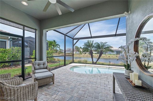 view of swimming pool featuring a water view, ceiling fan, a lanai, and a patio