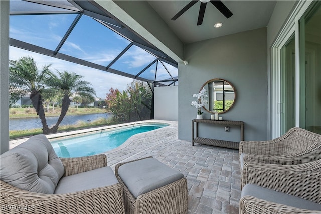 view of pool with a patio area, glass enclosure, a water view, and ceiling fan