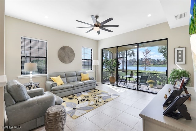 living room with ceiling fan, light tile patterned flooring, and a water view