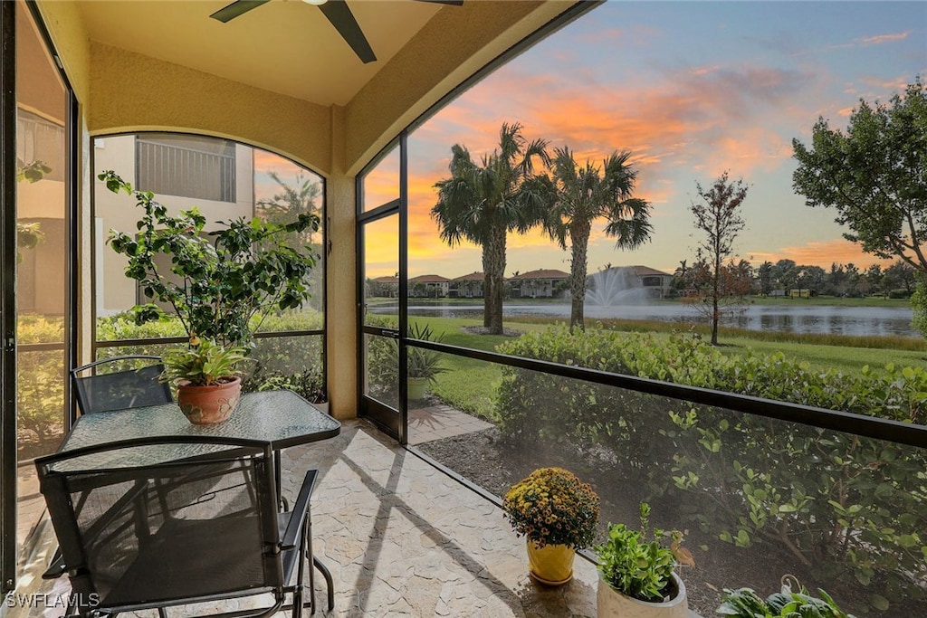 sunroom / solarium with ceiling fan and a water view