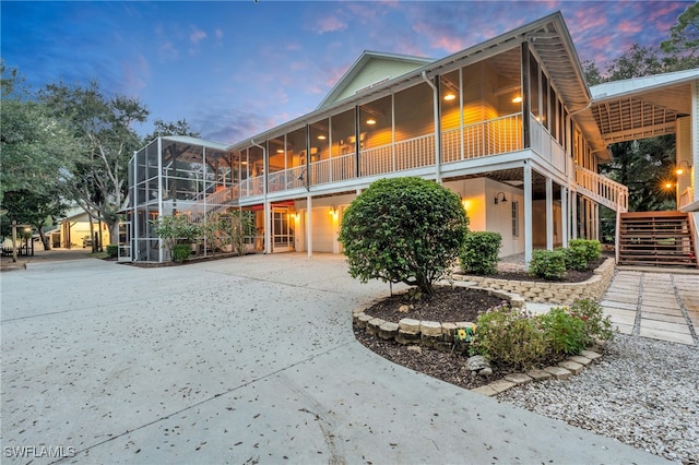 back house at dusk with a patio and glass enclosure