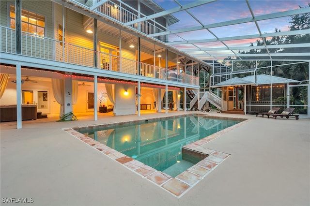 pool at dusk with a patio and a lanai