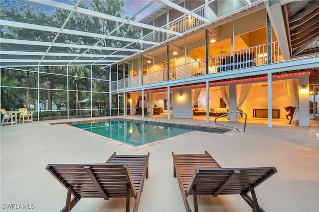 pool at dusk featuring a patio and a lanai