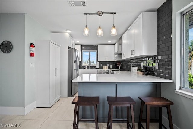 kitchen featuring plenty of natural light, appliances with stainless steel finishes, kitchen peninsula, and white cabinets