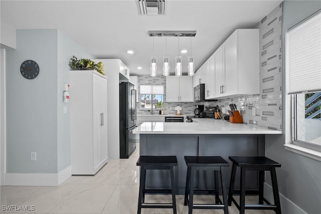 kitchen featuring a healthy amount of sunlight, appliances with stainless steel finishes, kitchen peninsula, and white cabinetry