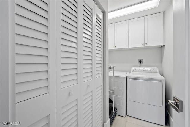 clothes washing area featuring cabinets, washer and clothes dryer, and light tile patterned floors