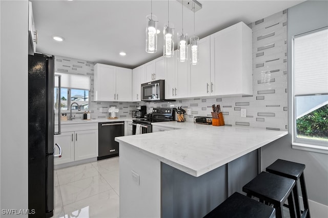 kitchen with kitchen peninsula, a healthy amount of sunlight, backsplash, a kitchen bar, and black appliances