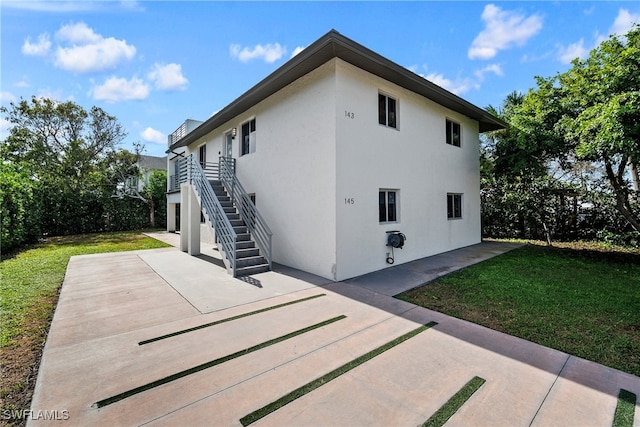 view of side of property featuring a yard and a patio