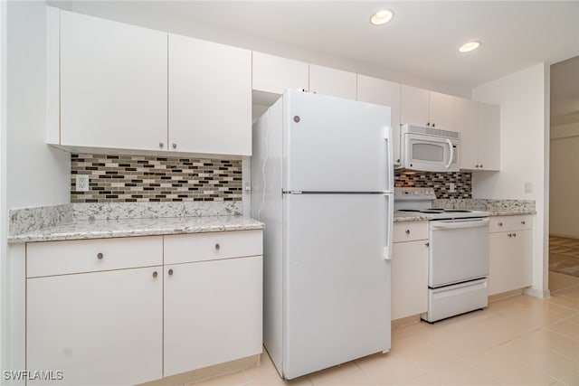 kitchen featuring white appliances, backsplash, light stone countertops, and white cabinets