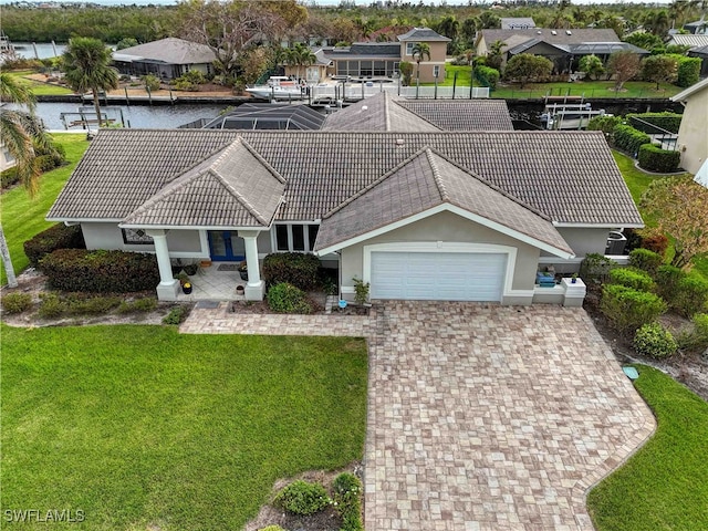 view of front of property featuring a garage, a water view, and a front lawn