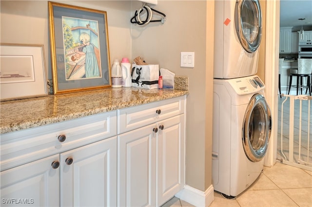 laundry room featuring stacked washer and clothes dryer and light tile patterned flooring