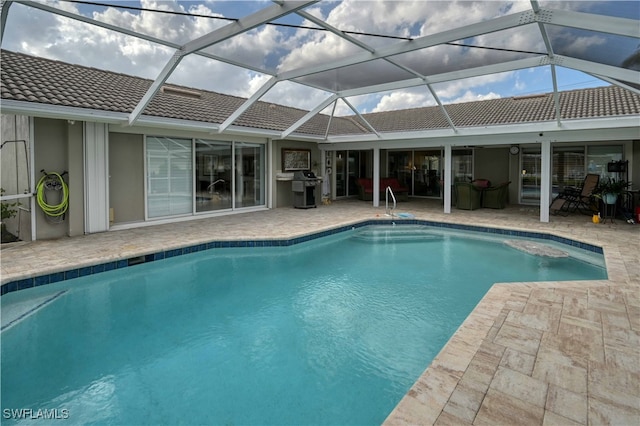 view of swimming pool featuring glass enclosure, a patio area, and grilling area