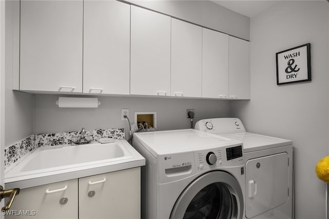 clothes washing area featuring sink, washing machine and clothes dryer, and cabinets