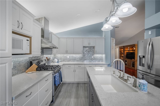 kitchen featuring lofted ceiling, white cabinets, stainless steel appliances, and wall chimney exhaust hood