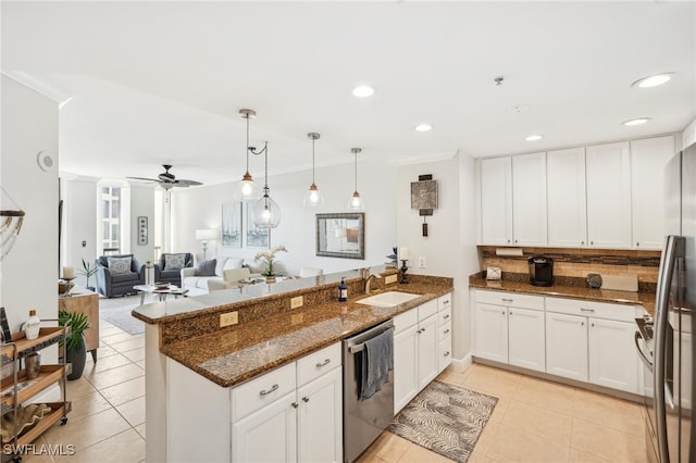 kitchen with appliances with stainless steel finishes, kitchen peninsula, white cabinets, and light tile patterned flooring