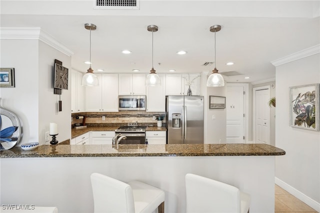 kitchen featuring appliances with stainless steel finishes, kitchen peninsula, white cabinets, and hanging light fixtures