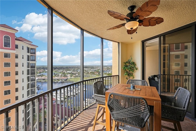 sunroom featuring a water view and ceiling fan