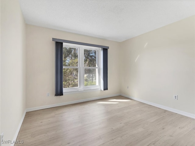 empty room with a textured ceiling and light wood-type flooring