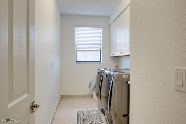 laundry area featuring light tile patterned flooring, washing machine and clothes dryer, and cabinets