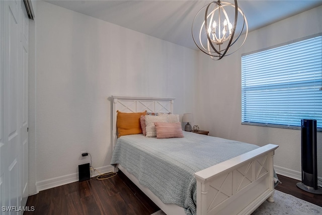 bedroom with a closet, dark wood-type flooring, and a chandelier